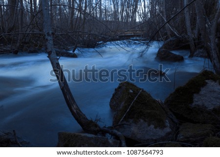 Wet stones in the foreground, spring flood of a usually small river in a forest in northern Sweden. Long exposure, making the water looking like clouds.