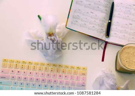 Colorful Computer Keyboard surrounded with Iris flower,  notebook and coffee cup Royalty-Free Stock Photo #1087581284