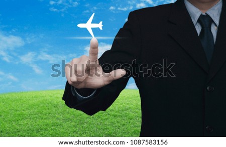 Businessman pressing airplane icon over green grass field with blue sky, Business transportation concept
