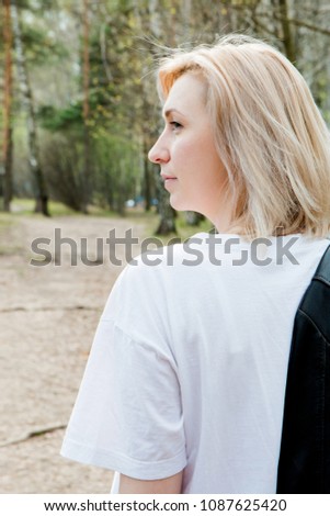 profile portrait of smilling blonde young girl in the forest close-up.