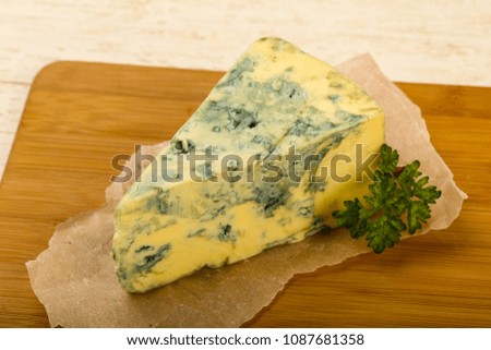 Blue cheese with parsley over wooden background