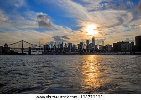 Famous Manhattan and Brooklyn Bridges in New York City, USA with financial district, downtown Manhattan in background. East River and beautiful sunset reflection