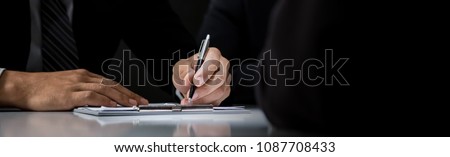 Businessman signing contract at the table in dark room, panoramic banner background with copy space Royalty-Free Stock Photo #1087708433