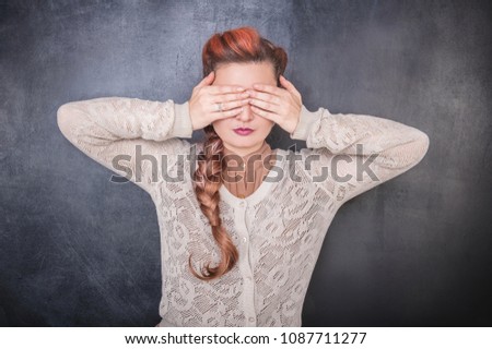 Stylish woman covering her eyes with hands on the chalkboard blackboard background