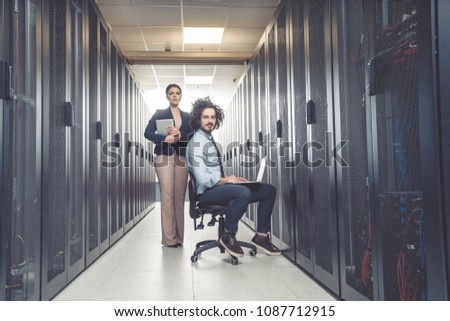 Man and woman working on servers at data center. server room