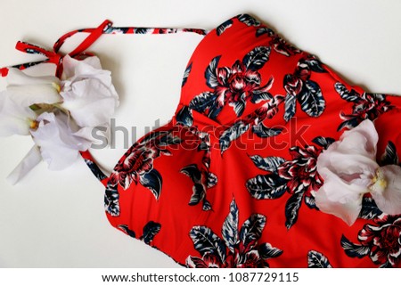 Swimsuit with tropical print on white wooden background.woman's swimwear and beach accessories. Royalty-Free Stock Photo #1087729115