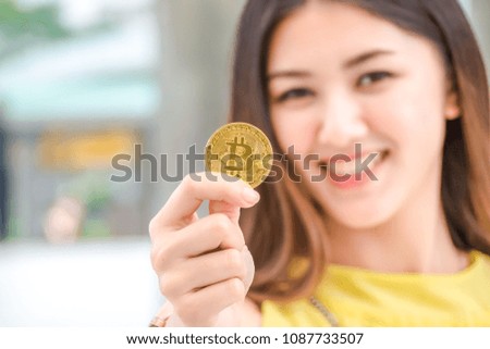  Shopping woman holding golden bitcoin to shopping online via smart phone at walkway.
