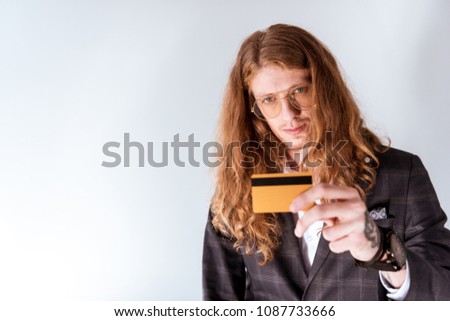 stylish tattooed businessman with curly hair showing credit card