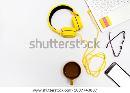 Yellow earphones, notebooks, coffee cups, glasses and mobile. Placed on a white background.