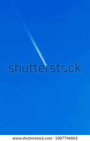flying aircraft in the sky white stripe. Airplane in the blue sky leaves white stripes behind him. The direction is diagonal. It can be used as a background. Space for text.