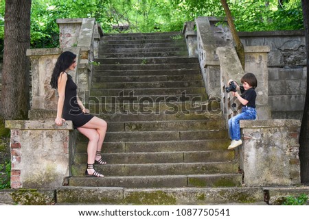 Little boy taking photo of beautiful girl. Child take pictures of woman on stairs