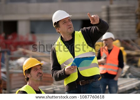 Civil engineer giving instructions to construction workers on construction site Royalty-Free Stock Photo #1087760618