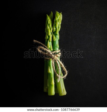 Asparagus. Bunch of fresh green asparagus tied on black background. Healthy vegetarian food. Square image Royalty-Free Stock Photo #1087766639