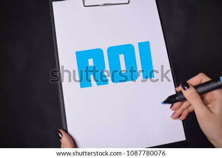In the hands of a businessman a notebook with the inscription:ROI