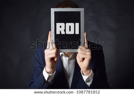 In the hands of a businessman a frame with the inscription:ROI