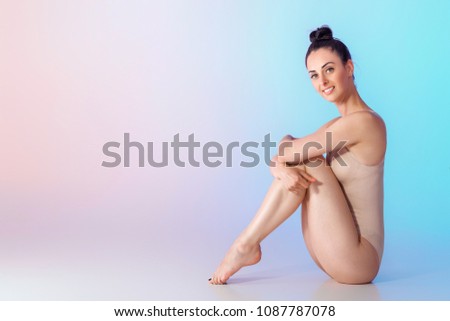 beautiful smiling gymnast in beige swimsuit on blue background