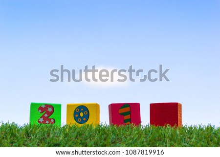 Wood block squre shape paint number in each a piece for use for use meaning is happy new year on green grass and a blue sky background