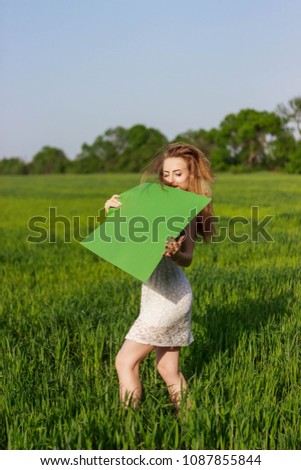 Beautiful girl with a poster in an open wheat field