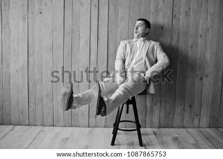 Studio portrait of man in suit against wooden background.