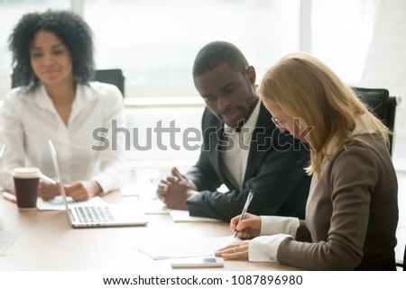 Caucasian businesswoman signing business document making deal at meeting with african partners, female client customer puts written signature on contract buying insurance services, taking bank loan Royalty-Free Stock Photo #1087896980