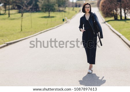 attractive girl walking on park road in sunny day in dark suite