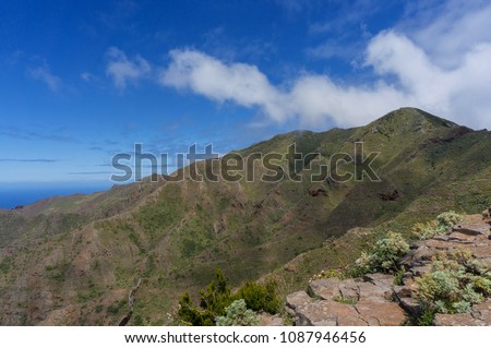 Hilly Landscape with Ocean in Background. Clouds above the hill and bright blue sky.