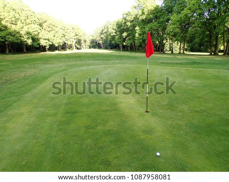 Golf green with flag and ball, Chorleywood Common Royalty-Free Stock Photo #1087958081