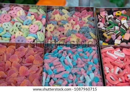Assortment of sweets and candies on lots of shapes and colors at a market stall.