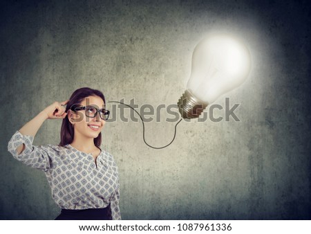 Smiling beautiful young woman having an idea with light bulb over her head Royalty-Free Stock Photo #1087961336