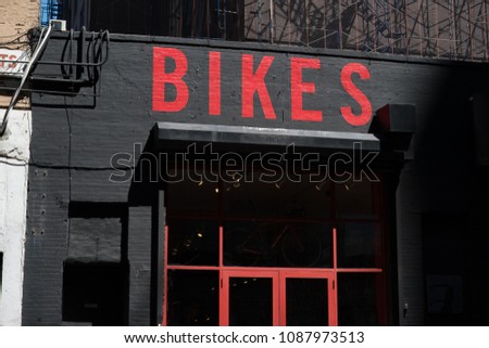 Exterior of a generic bike shop in New York. Bikes painted in red on black brick building. Generic bicycle storefront painted red and black. Facade of a bike store in an urban area, USA.