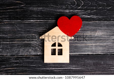 Wooden house with a red heart on a background of black wooden boards. A notification icon for the application. Love nest, love relationships. Buying a house with a young family. Affordable housing
