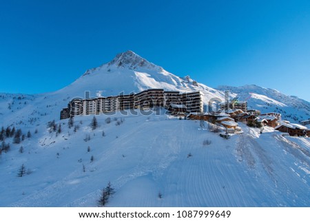 Pictured in background snow covered Mountain Pas de la Tovière. Perched on mountain edge is chalet apartments and the edge of Tignes Le Lac 2100 village, French Alps, France. 