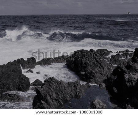 
Sea view with light waves and volcanic rock in the foreground, picture in black and white