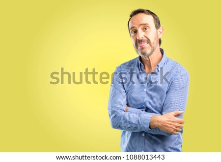 Handsome middle age man sticking out tongue at camera at sign of disobedience, protest and disrespect