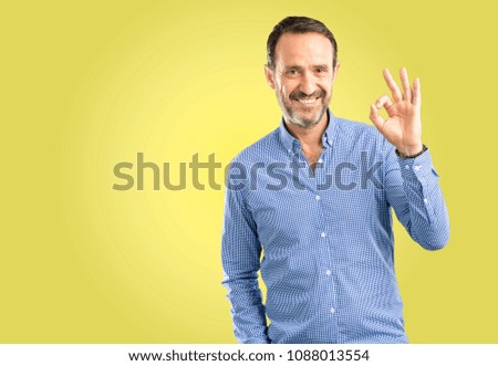 Handsome middle age man doing ok sign with hand, approve gesture