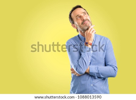 Handsome middle age man thinking and looking up expressing doubt and wonder