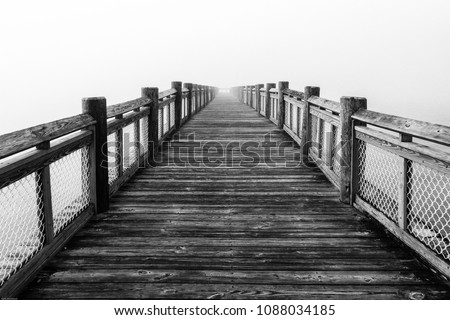 Black And White Photo of a Wooden Pier in Fog at Sunrise