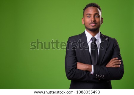 Studio shot of young handsome African businessman against green background