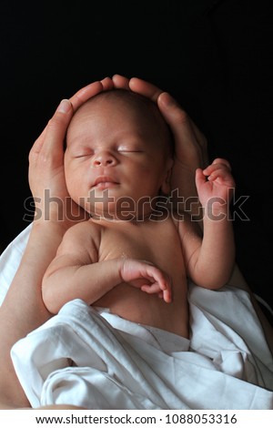 baby in mother's arms and wrapped up in white blanket stock image just been cared for after having a good sleep in bed stock photo Royalty-Free Stock Photo #1088053316