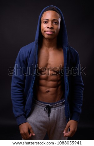 Studio shot of young handsome African man against black background