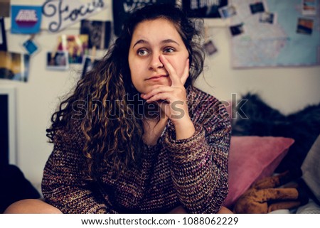 Confident teenage girl sitting in a bedroom with a peace sign