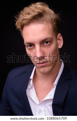 Studio shot of young handsome Scandinavian businessman against black background