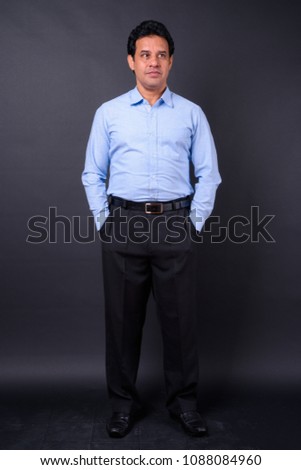 Studio shot of mature Indian businessman against black background