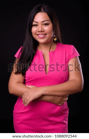 Studio shot of overweight Asian woman against black background