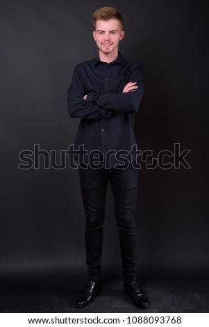 Studio shot of young handsome businessman against black background
