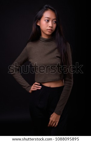 Studio shot of young beautiful Asian woman against black background