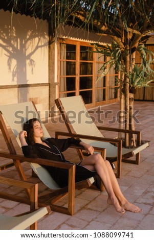 girl chilling in front of the room on the sunrise near the pool in bathrobe on sunlight