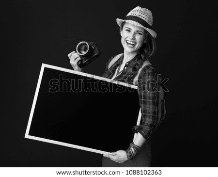 Searching for inspiring places. smiling fit tourist woman in a plaid shirt with DSLR camera showing blank board against background