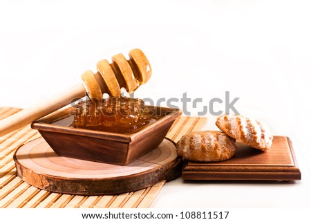 Sweet honey from honeycombs in a wooden bowl and biscuits on a white background