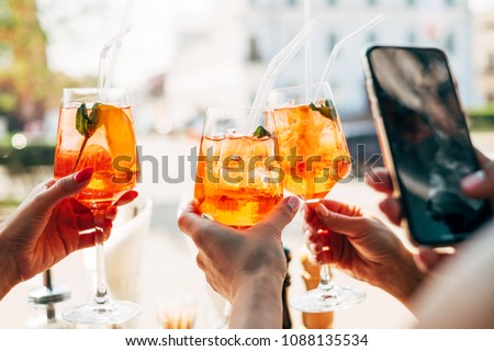 Girls holding alcoholic drinks and taking photo on her smartphone Royalty-Free Stock Photo #1088135534